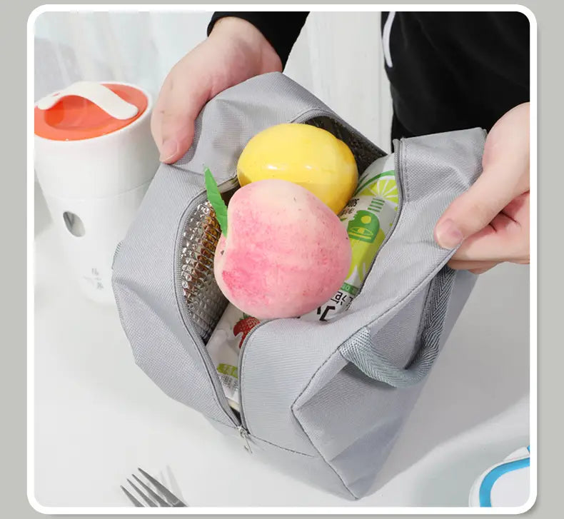 Insulated lunch bag is unzipped showing bottle of juice and two pieces of fruit inside.